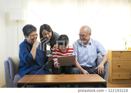 Happy Asian family having fun watching online video with Tablet in living room at home. 122193228