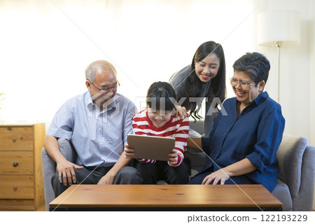 Happy Asian family having fun watching online video with Tablet in living room at home. 122193229
