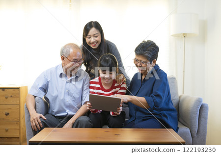Happy Asian family having fun watching online video with Tablet in living room at home. 122193230
