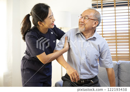 Medical assistance. Asian female nurse help Senior asian man getting up from the sofa while staying at the nursing home. 122193438