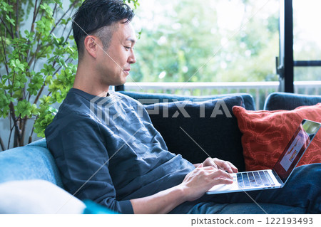 Man using a computer on the sofa 122193493