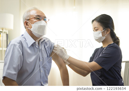 Medical worker perform a vaccine injection to senior Asian man in clinic or medical facility. Medical worker perform a vaccine injection to senior Asian man in clinic or medical facility. 122193634