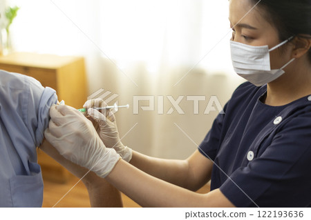 Medical worker perform a vaccine injection to senior Asian man in clinic or medical facility. 122193636