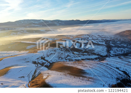 Aerial view of sunset over misty winter mountains 122194421