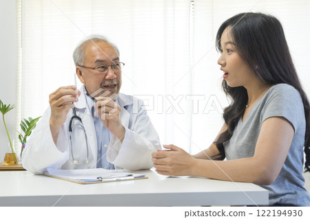 Senior Asian doctor talking with young female patient in hospital. 122194930