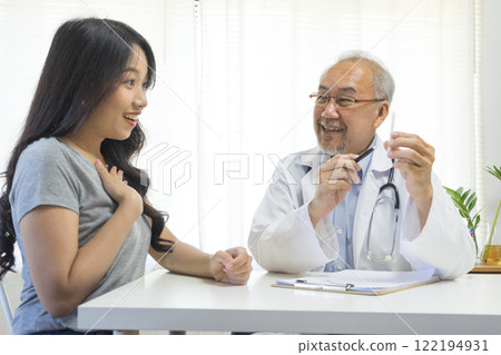 Senior Asian doctor talking with young female patient in hospital. 122194931