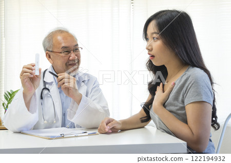 Senior Asian doctor talking with young female patient in hospital. 122194932