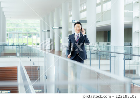 A businessman operating a smartphone in a hallway A businessman operating a smartphone in a hallway 122195102