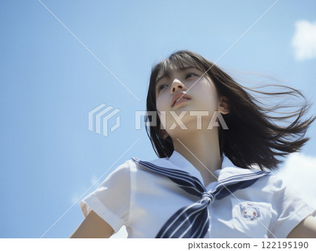 A high school girl standing under the blue sky, her hair fluttering in the wind 122195190