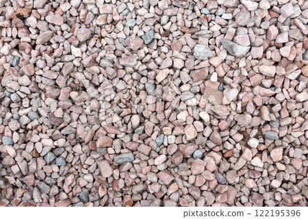 A texture-rich close-up of small, rough gravel stones in shades of pink, gray, and beige. The natural uneven surface and dispersed colors provide an organic appeal. Background for design projects. 122195396