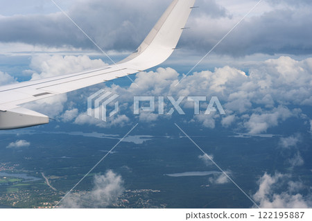 Wings, clouds and the ground as seen from an airplane window 122195887