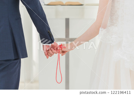 A bride and groom tied with a red thread at a wedding hall (bridal wedding) A bride and groom tied with a red thread at a wedding hall (bridal wedding) 122196411