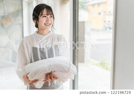 拿著洗過的浴巾的家庭主婦婦女 拿著洗過的浴巾的家庭主婦婦女 122196729