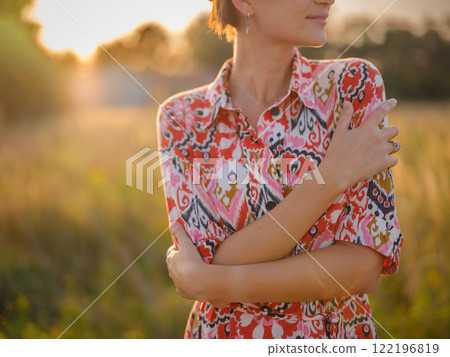 young woman embracing herself, self-love in action, mental health advocate, practicing self-care for finding inner peace, in European countryside 122196819