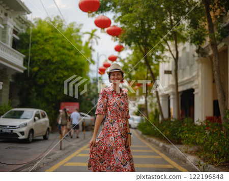 Young woman in ethnic dress and hat exploring the festive streets of George Town, Malaysia, during Chinese New Year. Vibrant lanterns, cultural celebrations, and historic charm create a unique 122196848