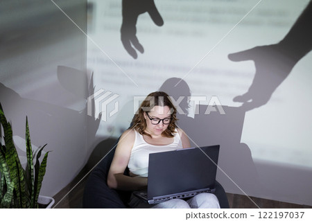 A woman works on her laptop, with shadows symbolizing digital threats around her A woman works on her laptop, with shadows symbolizing digital threats around her 122197037