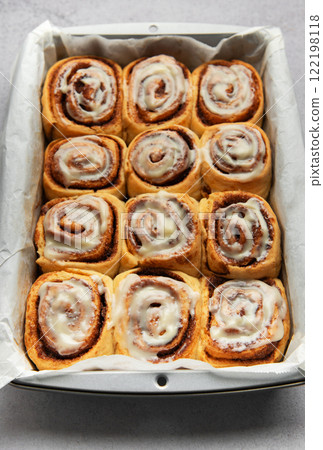 Freshly baked cinnamon rolls drizzled with icing in a baking pan 122198118