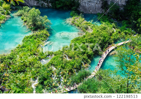 Scenic view Plitvice lakes turquoise waters surrounded by lush greenery rocky cliffs Croatia National Park with wooden pathways for visitors tourists to explore. Stunning nature greenery landscape 122198513