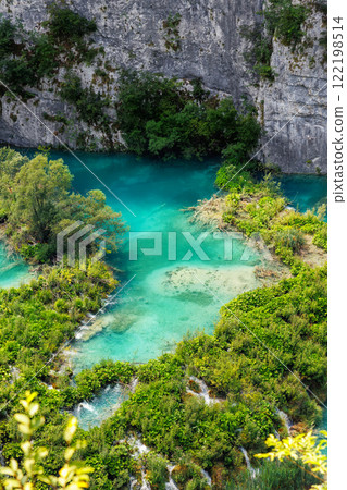 Scenic view Plitvice lakes turquoise waters surrounded by lush greenery rocky cliffs Croatia National Park with wooden pathways for visitors tourists to explore. Stunning nature greenery landscape 122198514