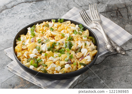Spicy Mexican corn potato salad with hard boiled eggs, onions and pickled jalapenos and cheese close-up in a plate. horizontal 122198985