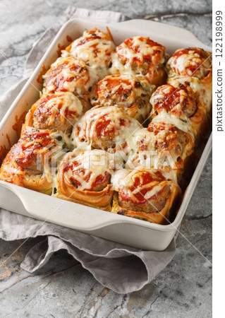 Meatball Stuffed Garlic Bread Sliders topped with cheese closeup on the baking dish. Vertical Meatball Stuffed Garlic Bread Sliders topped with cheese closeup on the baking dish. Vertical 122198999