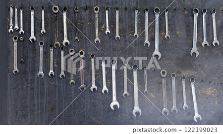 Hand tools neatly displayed on a vertical board in a workshop. An array of wrenches organized by size. This setup highlights precision, craftsmanship, and the essence of tools in mechanical work. Hand tools neatly displayed on a vertical board in a workshop. An array of wrenches organized by size. This setup highlights precision, craftsmanship, and the essence of tools in mechanical work. 122199023