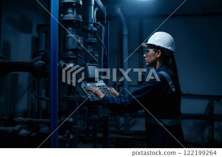 Engineer working on industrial machines, demonstrating technology, precision, skill, monitored systems, safety practices, manufacturing processes, technical expertise, 122199264