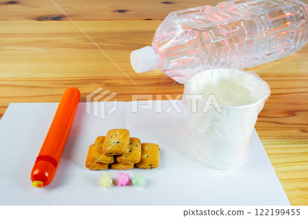 A paper cup filled with water and a food ration for one meal at a shelter, covered with a plastic bag A paper cup filled with water and a food ration for one meal at a shelter, covered with a plastic bag 122199455