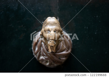 Bronze gargoyle door knocker on dark wooden door 122199688