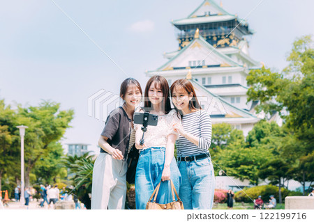 Three girls taking a selfie in front of Osaka Castle 122199716