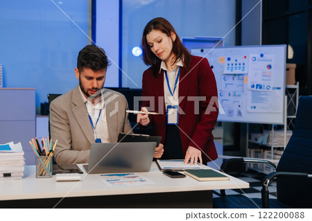 Diversity, business team working at office with laptop and documents on desk, financial adviser analyzing data, employees working overtime. Diversity, business team working at office with laptop and documents on desk, financial adviser analyzing data, employees working overtime. 122200088