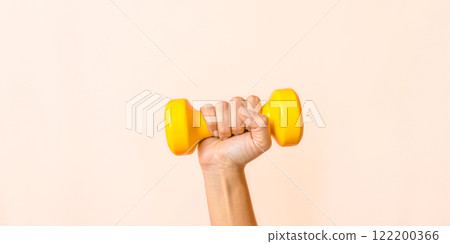 Fitness concept with hand holding yellow dumbbell, pink background, workout motivation, strength training, exercise equipment, gym accessory, home gym, physical activity, active lifestyle Fitness concept with hand holding yellow dumbbell, pink background, workout motivation, strength training, exercise equipment, gym accessory, home gym, physical activity, active lifestyle 122200366