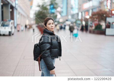 woman traveler visiting in Shanghai, China. Happy Female Tourist sightseeing in Nanjing road, shopping district of Shanghai. landmark and popular for tourism attractions. Travel and Vacation concept 122200420