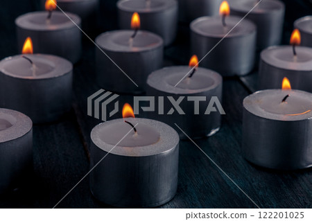 Tea light candles on a dark background, many lights in the dark 122201025