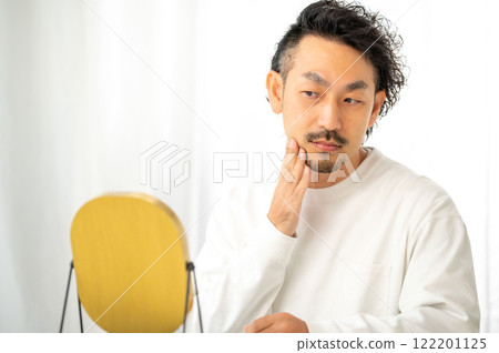 Japanese man checking his skin in the mirror Japanese man checking his skin in the mirror 122201125