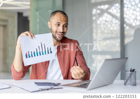 Smiling professional explaining statistical data while holding a chart and using a laptop, showcasing modern business communication. Smiling professional explaining statistical data while holding a chart and using a laptop, showcasing modern business communication. 122203151