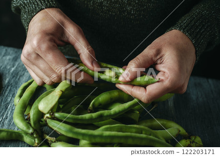 man shelling some broad beans at a table man shelling some broad beans at a table 122203171