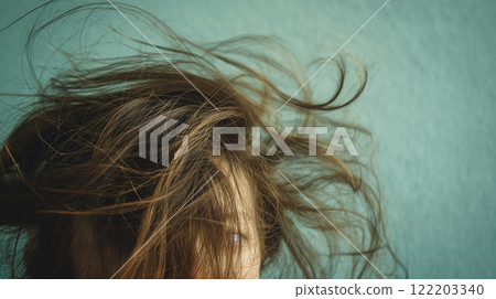 Tousled hair against a teal backdrop. 122203340