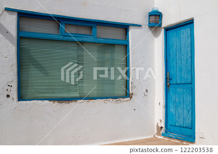 White weathered wall and a blue window and door, Spain 122203538
