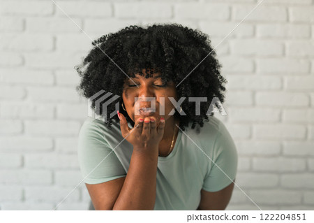 Catch my kiss. Lovely romantic African American woman air kissing over palms hands, sending love. Beauty care and Valentines day concept 122204851