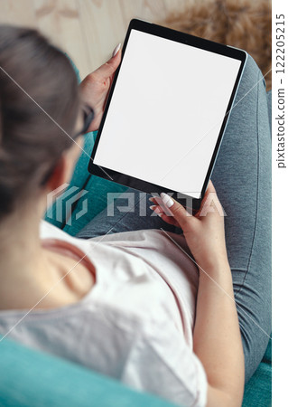 Young woman using digital tablet while sitting in a comfortable Young woman using digital tablet while sitting in a comfortable 122205215