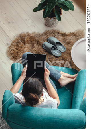 Young woman using digital tablet while sitting in a comfortable Young woman using digital tablet while sitting in a comfortable 122205234