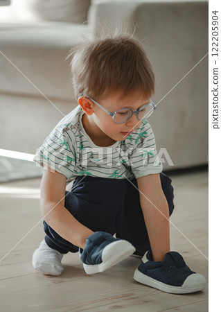 Child with autism in glasses play with his shoes Child with autism in glasses play with his shoes 122205904