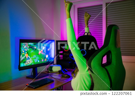 Winning. Young woman in gaming headphones playing video game online at home neon room feel excited, Happy Gamer young plays online video games computer she raises hands to wins tournament, E-Sport Winning. Young woman in gaming headphones playing video game online at home neon room feel excited, Happy Gamer young plays online video games computer she raises hands to wins tournament, E-Sport 122207061