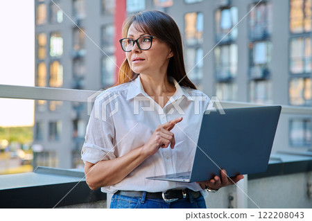 Mature serious businesswoman using laptop, outdoor urban style Mature serious businesswoman using laptop, outdoor urban style 122208043