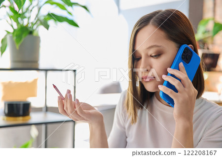 Headshot portrait of young serious woman talking on mobile phone in coworking 122208167