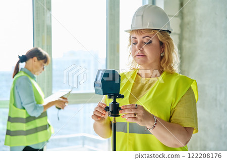 Woman industrial worker in protective vest helmet working on construction site Woman industrial worker in protective vest helmet working on construction site 122208176