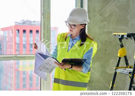 Technical profession woman in protective vest helmet working on construction Technical profession woman in protective vest helmet working on construction 122208178