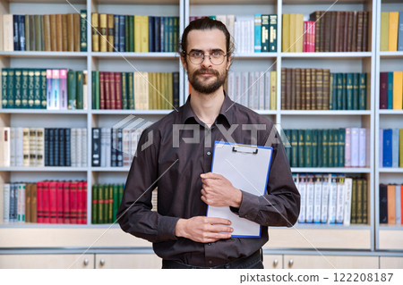 Portrait young male with clipboard in library Portrait young male with clipboard in library 122208187
