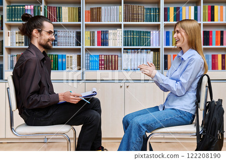 Teenage student girl talking with male teacher, social worker, school counselor in library Teenage student girl talking with male teacher, social worker, school counselor in library 122208190